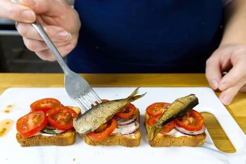 The process of preparing a festive snack on toast with sprats, onions, eggs and Stock Photos