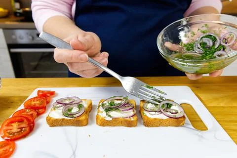 The process of preparing a festive snack on toast with sprats, onions, eggs and Foto stock