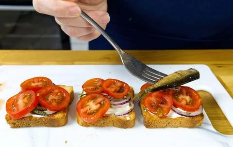 The process of preparing a festive snack on toast with sprats, onions, eggs and Stock Photos