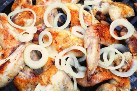 Process of preparing marinated chicken wings on the grill, chopped onion ring Foto stock