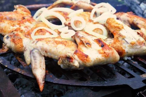 Process of preparing marinated chicken wings on the grill, chopped onion ring Stock Photos