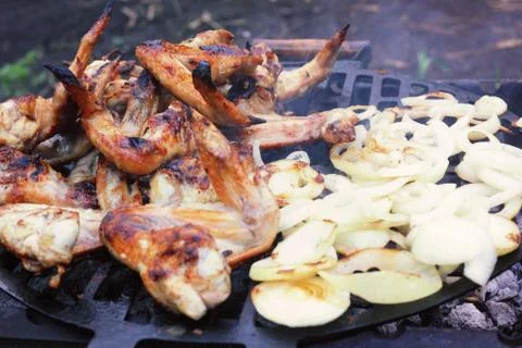 Process of preparing marinated chicken wings on the grill, chopped onion ring Foto stock