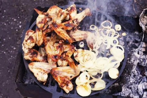 The process of preparing marinated chicken wings on the grill, chopped onion Stock Photos