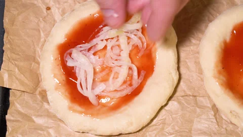 The process of preparing a mini pizza, adding onions Stock Footage 249881105