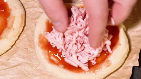 The process of preparing a mini pizza, laying out the sausage Видео 249880940