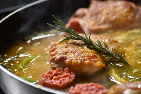 Process of preparing paella on a frying pan with rosemary, chorizo and chicke Foto stock