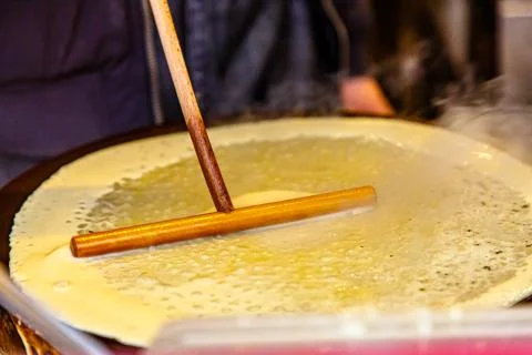 The process of preparing a pancake with a stick, which is leveled the dough.  Stock Photos