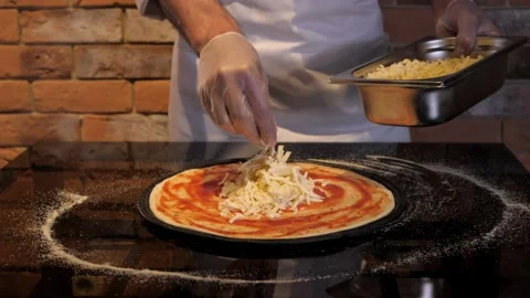 Process of preparing pizza. Cook puts cheese on flat cake made of raw dough Stock Footage 132427579