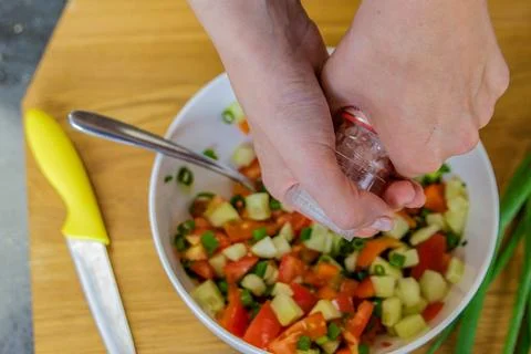The process of preparing salad. Close-up of a woman's hands pouring salt into Stock Photos