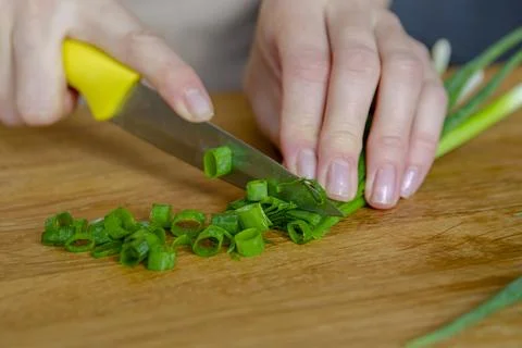 The process of preparing salad. A woman's hand chops a green onion close-up Stock Photos