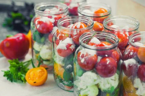 The process of preserving cucumbers and tomatoes for the winter. Stock Photos