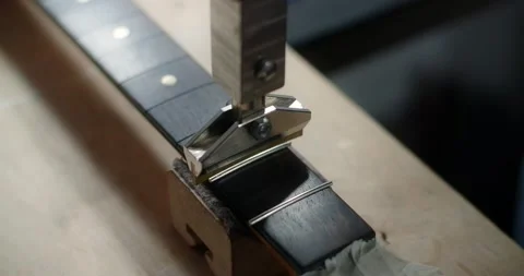 Process of press fitting the frets into the guitar fretboard at the luthier's Stock Footage 165875516