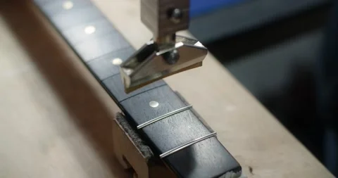 Process of press fitting the frets into the guitar fretboard at the luthier's Stock Footage 166218852