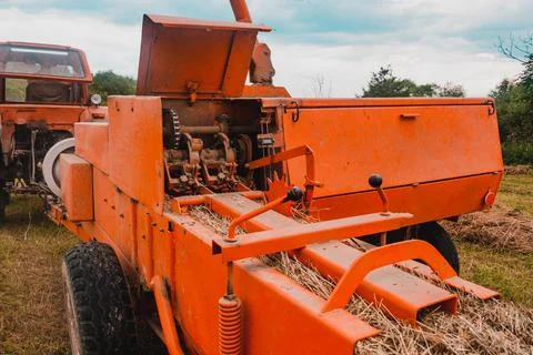 The process of pressing hay into bales, the work of the press machine, the me Stock Photos