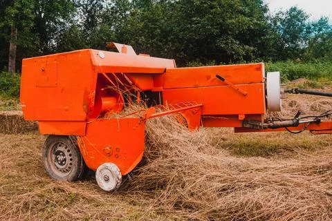 The process of pressing hay into bales, the work of the press machine, the me Fotos de archivo