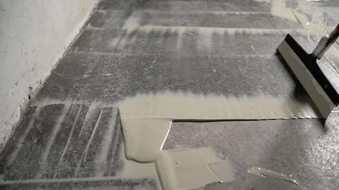 The process of priming the floor with a liquid solution using a spatula. The  Stock Photos