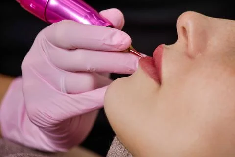 Process professional permanent lip makeup with lipstick effect for a young woman Stock Photos