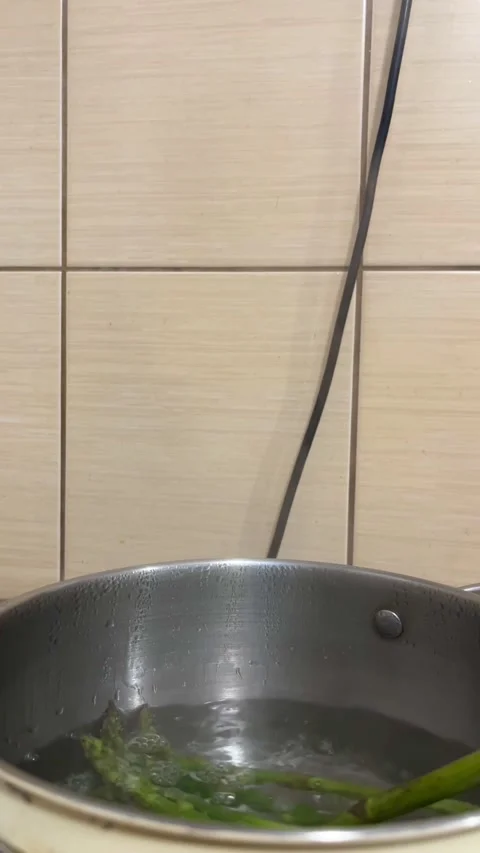 Process of pulling cooked green asparagus stalks with tongs in the kitchen Stock Footage 310409851