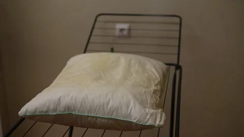 Process of purifying white pillow with steam on drying rack for cleanliness and Stock Footage 293841324
