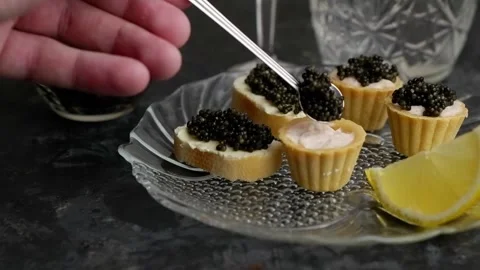 The process of putting black caviar into a tartlet with cream with a spoon. Stock Footage 170620489