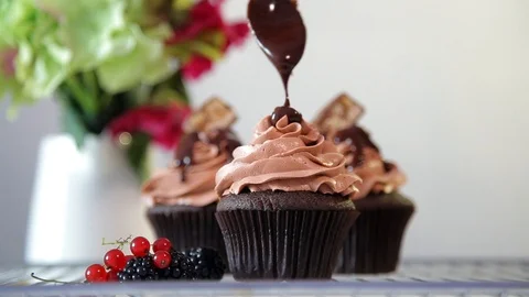 The process of putting chocolate coating on the top of the cupcake using spoon. Stock Footage 102932107