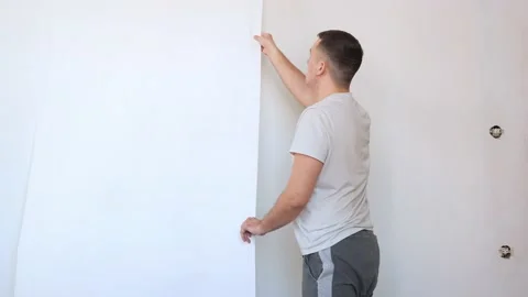 Process of removing old white wallpaper from the wall in the room during repairs Stock Footage 171661796