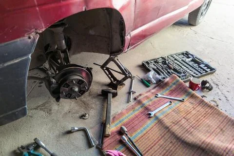 Process of repair an old red car with old poor tools on concrete surface 库存照片
