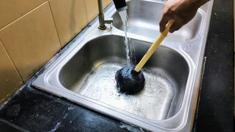 The process of repairing a kitchen sink that's clogged with food scraps and.. Фото