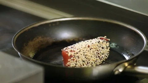 The process of roasting a tuna steak bunded in sesame on a hot pan. The cook Stock Footage 115660418