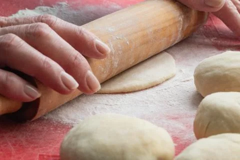 The process of rolling the dough with a wooden rolling pin, cooking bread at Stock Photos