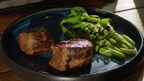 The process of serving grilled meat and asparagus dish on the plate, close-up Stock Footage 274818438