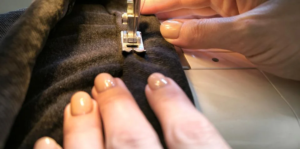 Process of sewing in a sewing machine sew woman's hands manicure black text.. Stock Photos