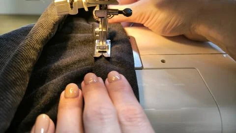 Process of sewing in a sewing machine sew woman's hands manicure black text.. Stock Photos