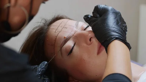 The process of shaping eyebrows with a thread for a lady, close-up of a face. Stock Footage 115850633
