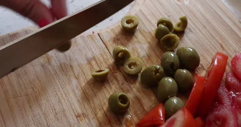 The process of slicing fresh green olives for salad preparation. Stock Footage 330393491
