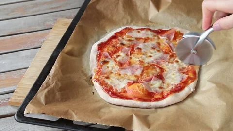 The process of slicing pizza at table . Fresh dough on kitchen table. Stock Footage 142476517