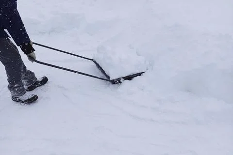 Process of snow removal with help of hand devices in the form of large scra.. Stock Photos