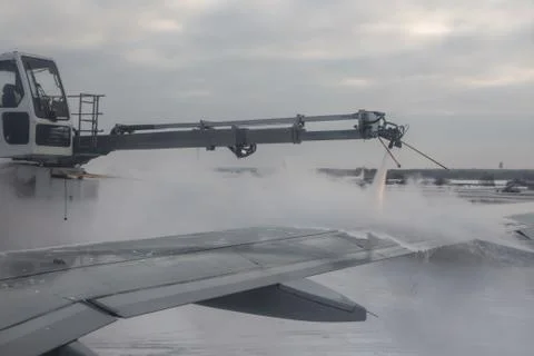 Process of spraying anti-icing white fluid the rear part of the wing of a pla Stock Photos