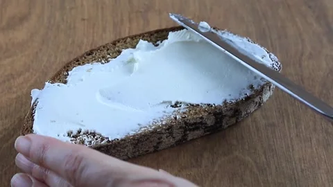Process of Spreading Cream Cheese on Dark Rye Bread Slice Stock Footage 346243366