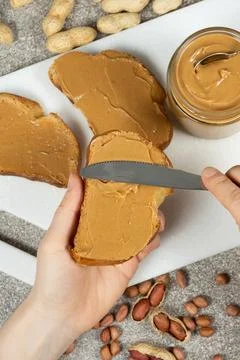 The process of spreading peanut butter on bread, hands close-up Stock Photos