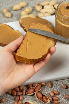 The process of spreading peanut butter on bread, hands close-up Fotos de archivo