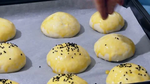 The process of sprinkling black cumin on the raw pastry dough on baking paper 動画素材 166705127