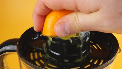The process of squeezing orange juice on a citrus juicer on an orange background Stock-Footage 297442795