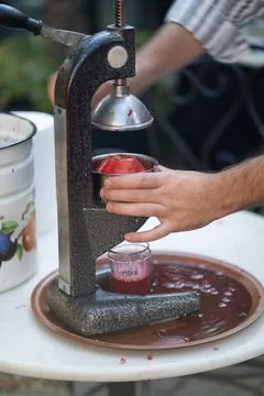 Process of squeezing pomegranate juice using manual mechanical juicer to obtain Stock-Fotos