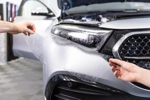 Process of sticking protect foil to the super, modern headlamp or headlight of Photos