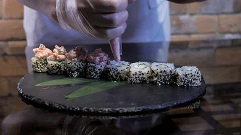 The process of sushi maki cooking, chef applying creamy tobiko tops on maki Stock Footage 135175262