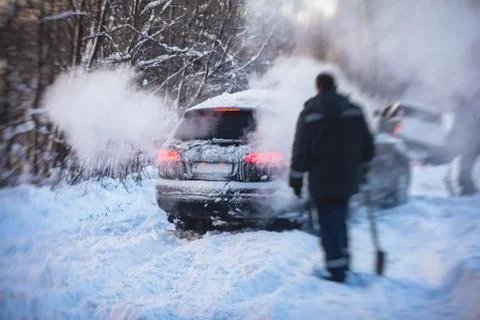 Process of taking out suv car stuck in snow, men digging and pushing the car  Stock Photos