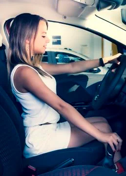 Process of testing vehicle. Beautiful blonde girl sitting in the new car with 스톡 사진