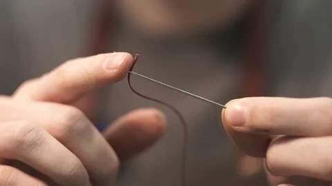 The process of threading a needle. The tanner has a thread before starting to Video stock 104927691
