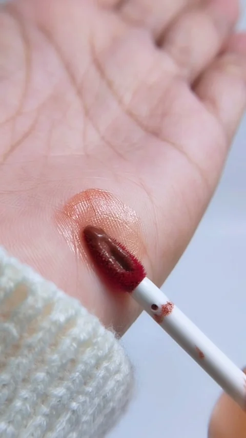 Process of trying or testing lip tint color on hand skin using a red brush... Stock Footage 340970994
